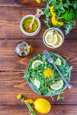 Karahindiba salatası zeytin yağı, limon suyu ve kahverengi ahşap masadaki baharatlardan yapılır. Üst görünüm