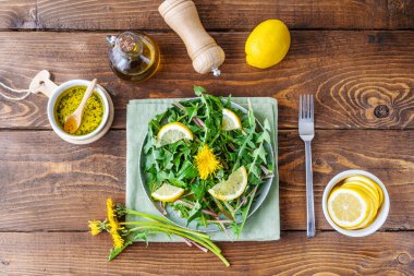 Karahindiba salatası zeytin yağı, limon suyu ve kahverengi ahşap masadaki baharatlardan yapılır. Üst görünüm