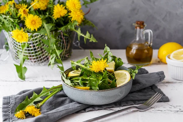 Salată de păpădie cu ulei de măsline, suc de lămâie și condimente pe masă albă din lemn cu fundal gri — Fotografie, imagine de stoc