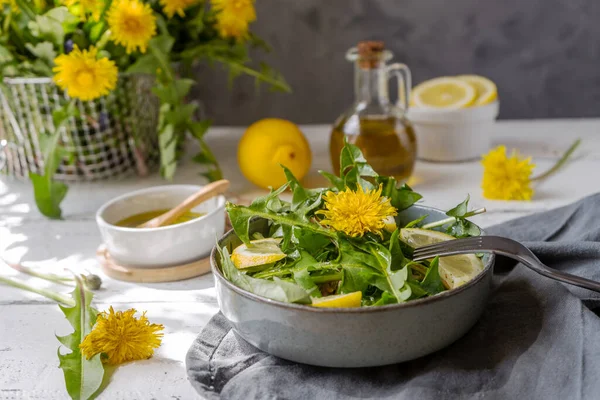 Dandelion salad with olive oil, lemon juice and spices on white wooden table with grey background — Fotografie, imagine de stoc