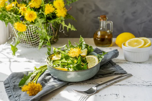 Salada de dente de leão com azeite, suco de limão e especiarias sobre mesa de madeira branca com fundo cinza — Fotografia de Stock