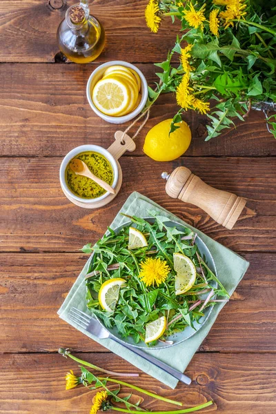 Salată de păpădie cu baie făcută cu ulei de măsline, suc de lămâie și condimente pe masa de lemn maro. Privire de sus — Fotografie, imagine de stoc