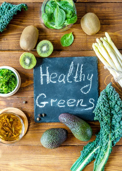 Healthy greens concept. Fresh kale, spinach, avocado, kiwi, seaweed, asparagus and green tea