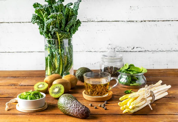 Healthy greens concept. Fresh kale, spinach, avocado, kiwi, seaweed, asparagus and green tea