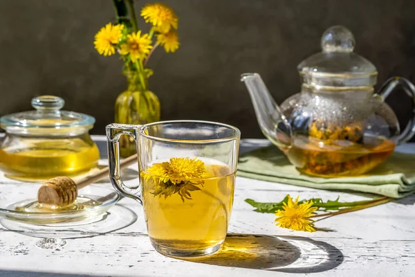 Dandelion honey and tea on the white wooden table with tea pot, dandelion flowers, mix for tea — Foto de Stock
