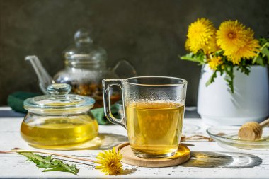 Karahindiba çayı ve bal beyaz ahşap masada çay demliği, karahindiba çiçeği, çay için kuru karışım