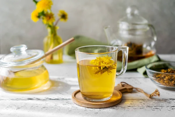 Dandelion tea and honey on the white wooden table with tea pot, dandelion flowers, dry mix for tea — Foto de Stock