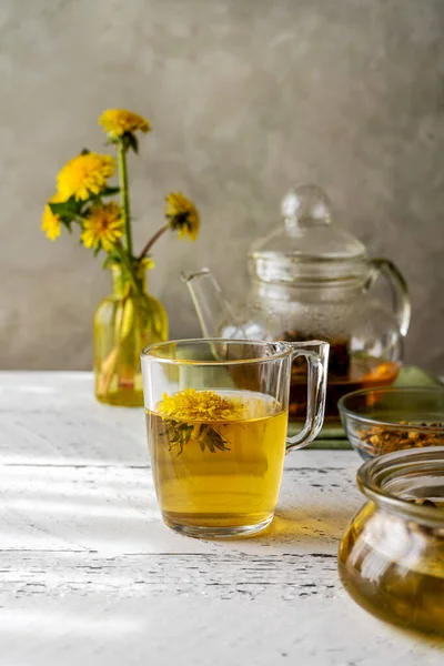Healthy herbal tea from dandelions on the white wooden table with tea pot, dandelion flowers, honey — Foto de Stock