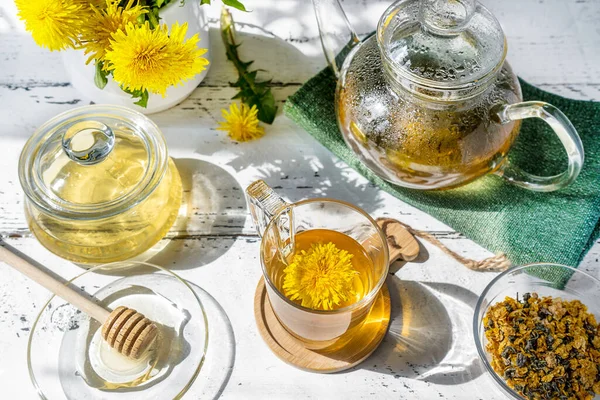 Dandelion tea and honey on the white wooden table with tea pot, dandelion flowers, dry mix for tea — Foto de Stock