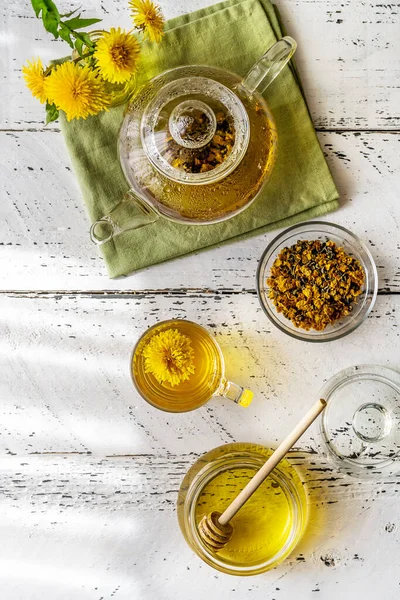 Dandelion tea and honey on the white wooden table with tea pot, dandelion flowers, dry mix for tea. Flat lay — Fotografie, imagine de stoc