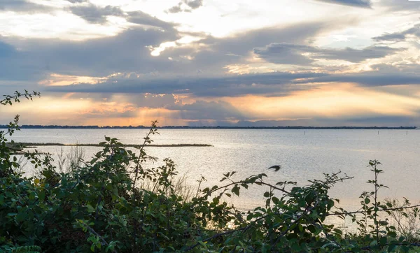 Güzel ve huzurlu bir gün batımı mavi bulutlar ve turuncu güneş sularda yansıyor.