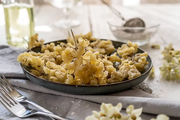 Acacia fried flowers on plate with napkin, forks, oil and sugar powder. Selective focus — Fotografie, imagine de stoc