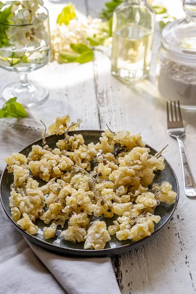 Acacia fried flowers on plate with napkin, forks, oil and sugar powder — стоковое фото