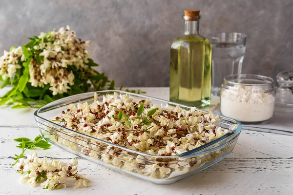 Acacia flowers in glass backing form with ingredients for cooking Acacia fritters. Concrete background 