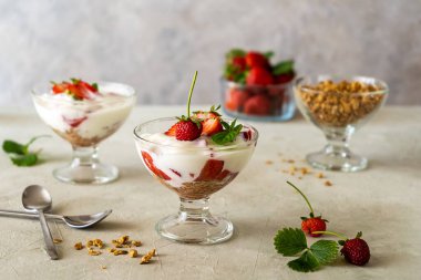 Çilek ezmeli yoğurt ve beyaz ahşap arka planda taze meyveli granola, peçete. Seçici odaklanma. Sağlıklı kahvaltı kavramı