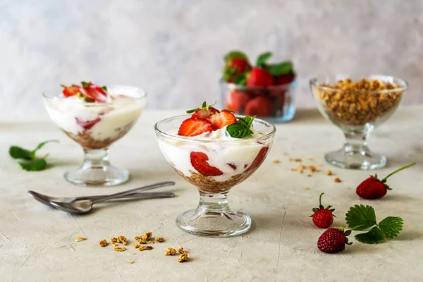 Çilek ezmeli yoğurt ve beyaz ahşap arka planda taze meyveli granola, peçete. Seçici odaklanma. Sağlıklı kahvaltı kavramı