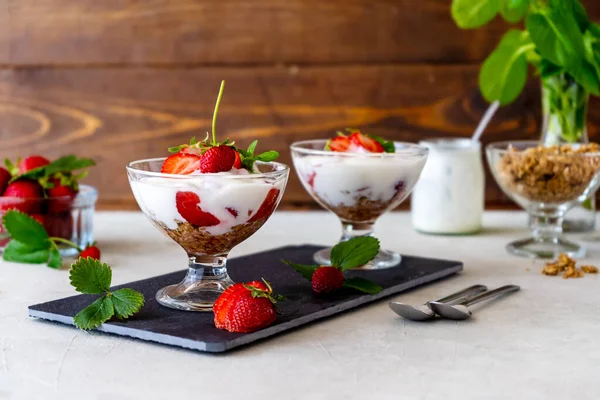 Çilekli yoğurt ve tatlı kabında taze meyveli granola. Ahşap arka plan. Seçici odaklanma. Sağlıklı kahvaltı kavramı