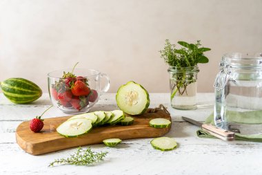 Erimiş suyun hazırlanması için çilek ve meloncella salatalık ve kavun karışımı kekik. Mutluluk kavanozu, tahta tahta, meyve kesme tahtası, bıçak. Nane. Uzayı kopyala. Detoks kavramı