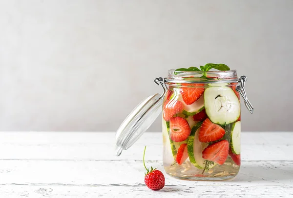 Infused water in glass jar with strawberry and a meloncella that is hybrid of cucumber and melon, thyme, Copy space. Healthy beverage concept without sugar added