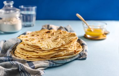 Ev yapımı Hint ekmeği Chapati ya da Roti mutfak havlusunun üzerinde tereyağlı kahve, su ve un. Geleneksel Asya ekmeği. Boşluğu kopyala