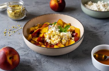 Nektarinli sağlıklı meyve salatası, şam fıstığı ve baldan yapılmış ricotta kreması. Somut bir geçmiş. Temel malzemeler ve çatal