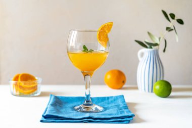 Sarı kuş kokteyli, rom, portakal ve limon suyu, beyaz arka planda meyveler, mavi peçete ve zeytin dallı vazo. Akdeniz tarzı. Boşluğu kopyala
