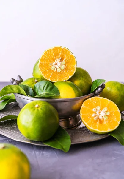 Mapo bir mandalina ve greyfurt karışımıdır. Düşük kalorili meyve bir vitamin ve mineral kaynağıdır. Biraz meyve ve antika teneke tabakta bir kesik. Kopyalama alanı olan gri arkaplan. 