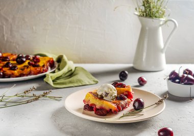 Tatlı vişneli turta mı yoksa çikolatalı kek mi? Bir parça tabakta dondurma, tüm pasta ve arka tarafta çiğ kiraz. Seçici odaklanma. Rustik Provence biçimi
