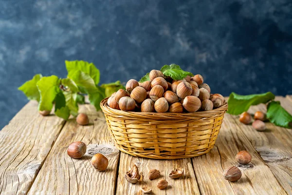 Sepette fındıklar ve yapraklar. Tahta masa, koyu gri arka plan. Boşluğu kopyala