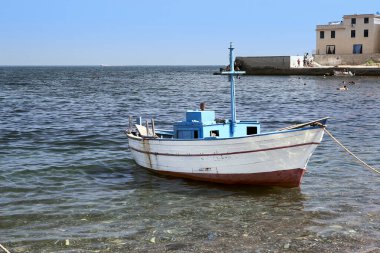 Sicilyalı bir balıkçı köyünün küçük bir limanına demirlemiş ahşap bir motorlu tekne.