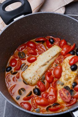 Stewed cod fillets with cherry tomatoes, black olives, onions, broth, parsley