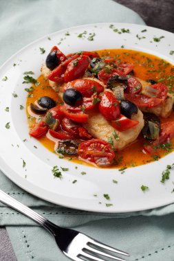 Stewed cod fillets with cherry tomatoes, black olives, onions, broth, parsley