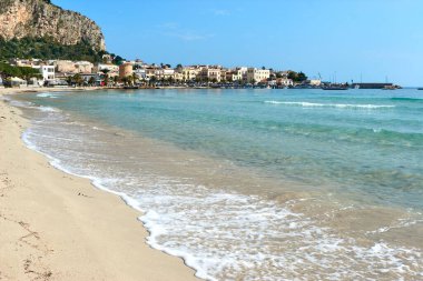 Gulf of Mondello, clear emerald sea, blue sky and seaside village in the background