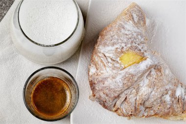 Limon sarısı krema ve ricotta ile kokulu sıcak kruvasanlar, yanında da güzel bir bardak süt ve espresso kahvesi.