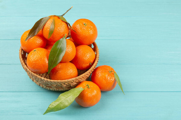 Freshly picked mandarins in a basket on a blue wooden background