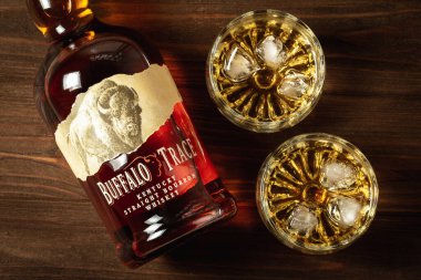 Ternopil, Ukrayna - 29 Nisan 2021: Bir şişe Buffalo Trace Kentucky sek viski ve ahşap bir masanın üzerinde buzlu ve burbonlu iki bardak