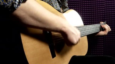 Bir adam gitar çalar ve akorları düzenler.