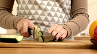 beautiful girl cuts cucumber for salad