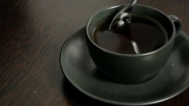 a person stirs sugar in hot tea