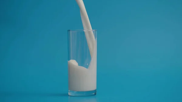 Mavi arka planda bir bardak süt.