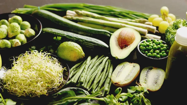 yeşil sebzeler ve meyveler masada.