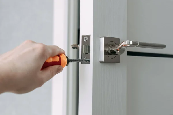 A handyman repair the door lock in the room. The concept repair yourself. Selective focus.