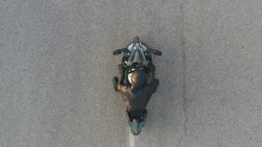 Motosikletlinin lastikleri patlatırken çok duman çıkıyor. Hareket başladığında motosiklet tekeri yolda kayıyor. Spor motosiklet çarkı asfalt yolda dönmeye başlar. Yavaş çekim Havadan çekim