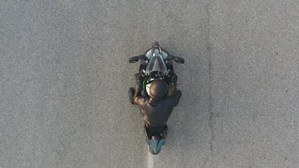 Vista superior do motociclista realizando burnout pneu com muita fumaça. Roda de motocicleta são deslizamento na rota durante o início do movimento. Roda de moto esporte começa a girar na estrada de asfalto. Movimento lento Tiro aéreo — Vídeo de Stock