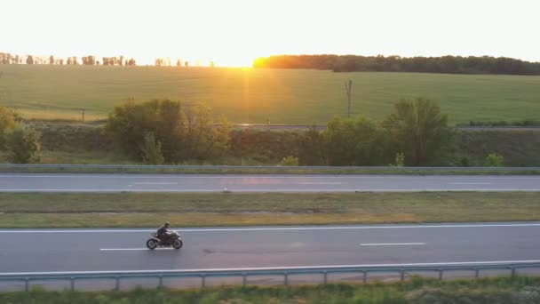 从空中观看骑自行车的人在高速公路上骑现代摩托车.骑摩托车的人在有阳光背景的乡间路上骑摩托车.人在旅行时骑自行车.自由和冒险的概念 — 图库视频影像