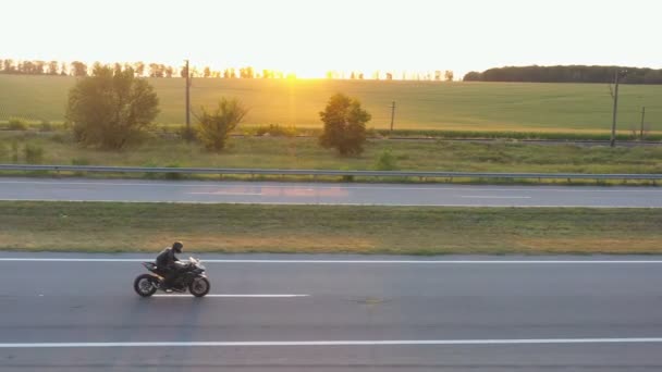 Anayolda motosikletle gezen motosikletlilere hava manzarası. Motosikletli arka planda güneşle kır yolunda motosikletiyle yarışıyor. Yolculuk sırasında bisiklet süren bir adam. Özgürlük ve macera kavramı — Stok video