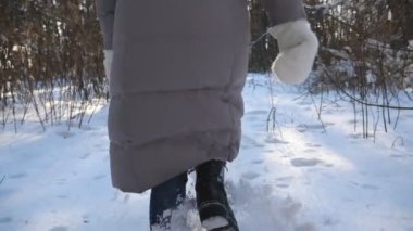 Kışlık giysiler içinde tanınmayan bir kadın karlı ormanda koşuyor ve kara basıyor. Soğuk kış gününde koşan kadın yürüyüşçülerin bacaklarının arkası. Kız dışarı çıkıyor. POV Ağır çekim Yakın çekim