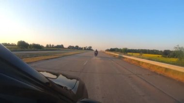 Golf yolunda motosikletiyle yarışan motosikletliyi takip eden arabadan görüş açısına göre. Yolculuk sırasında bisiklet süren adam. Kasklı genç adam otoyolda modern spor motosiklet kullanıyor. Yavaş çekim POV