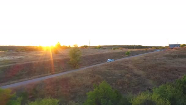 Aerial view of electrical car driving on country road with bright sunset at background. Modern vehicle moving fast along rural highway. Ecology friendly auto riding on electric charge — Stock Video