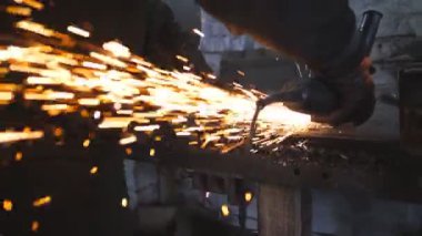 Ustabaşı metal kesmek için testere kesme makinesi kullanıyor. Garajda ya da atölyede çeliği kesen dairesel testereli bir adam. Metal öğüten endüstriyel işçiler. Sıcak metalden kıvılcımlar çıkıyor. Yavaş çekim